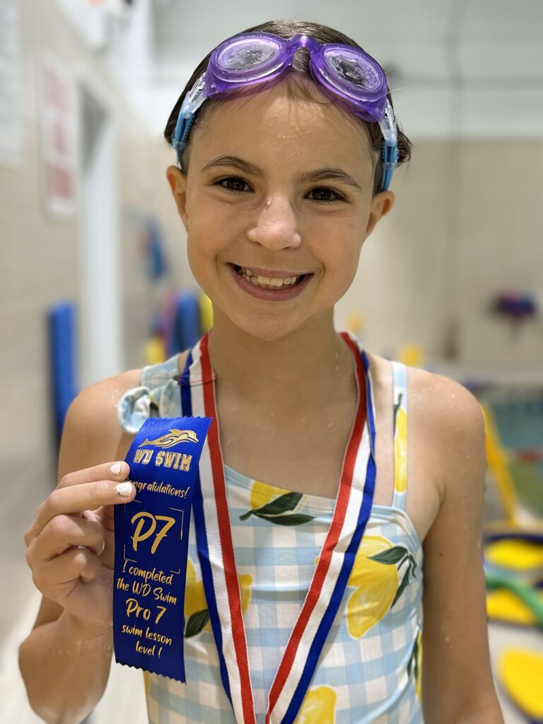 Smiling swimmer with her Pro level ribbon and medal at WD Swim Richmond Hill