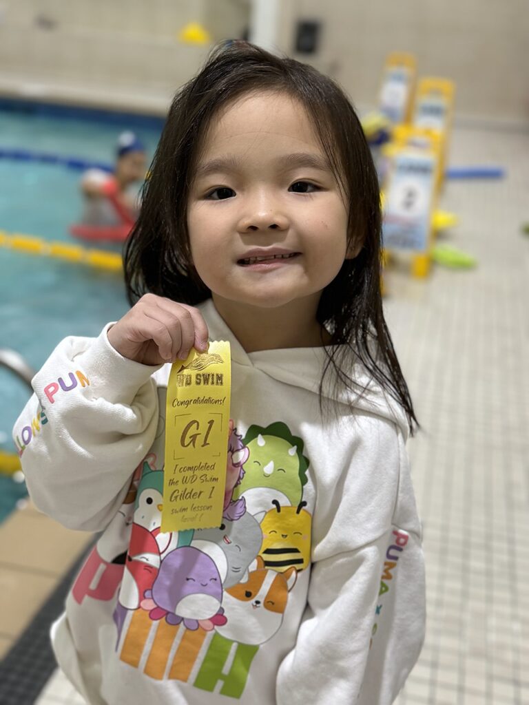 Young swimmer holding her Glider level ribbon at WD Swim Richmond Hill