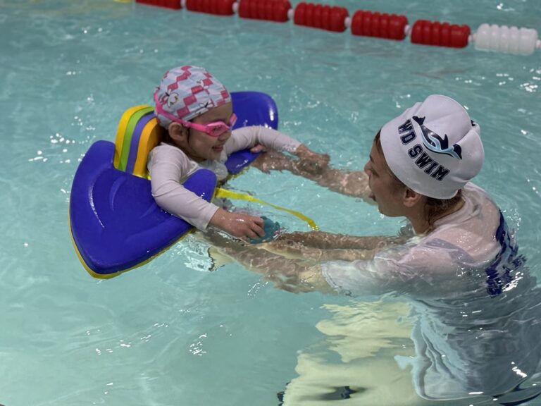 Coach supporting a toddler on a kickboard at WD Swim Richmond Hill