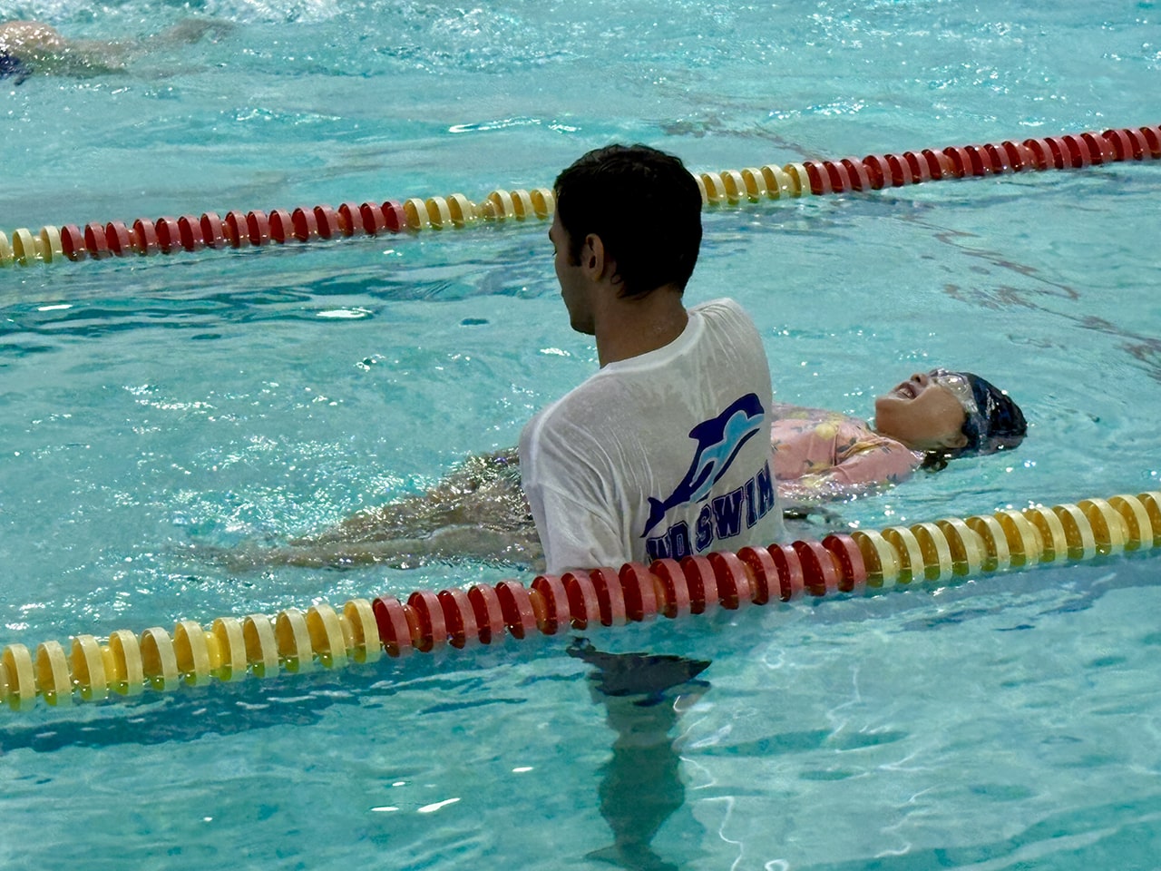 Coach guiding a swimmer through backstroke at WD Swim North York