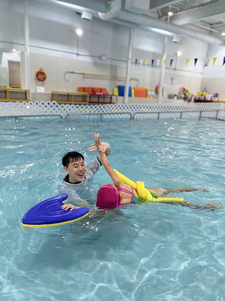 Coach guiding a young swimmer on her back at WD Swim Markham